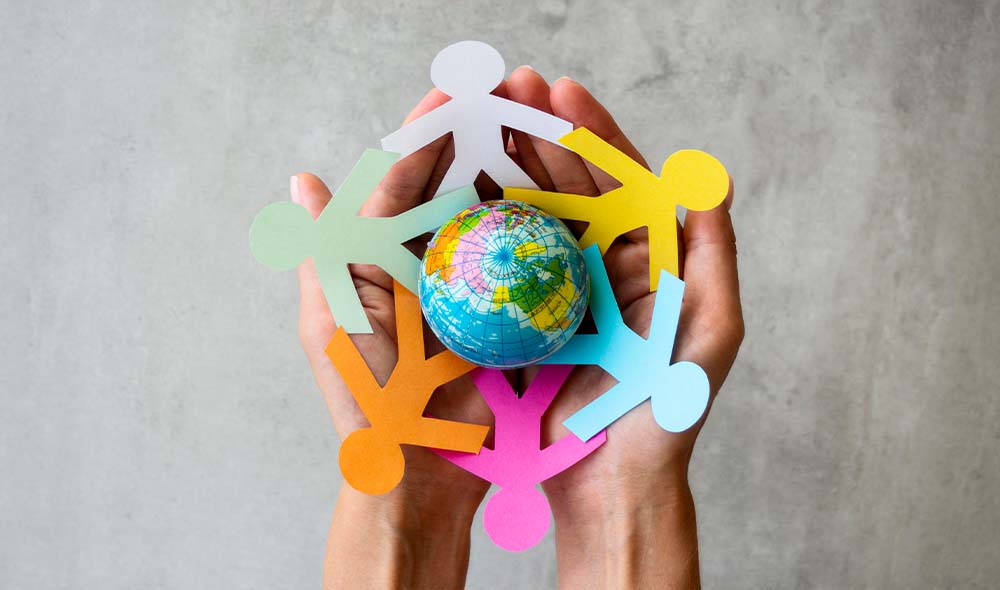 Mãos segurando pessoas de origami ao redor de um globo